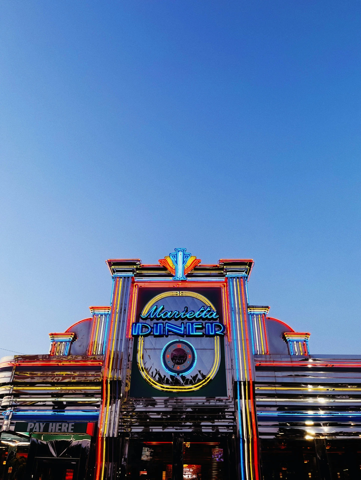 Marietta Diner neon sign and stainless-steel exterior beneath a blue sky in Marietta, Georgia